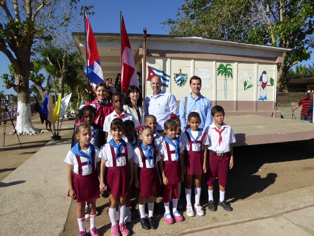 eine Gruppe von Schülerinnen und LehrerInnen vor kubanischer Flagge